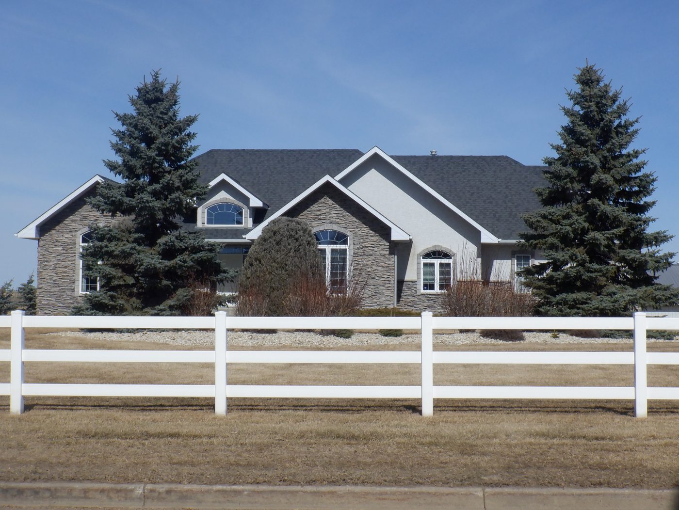 Home with new roof behind a white fence
